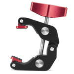 Close-up of a Super Clamp with a red adjustment knob and black metal body, featuring textured rubber grip pads and silver tension screws for secure mounting.